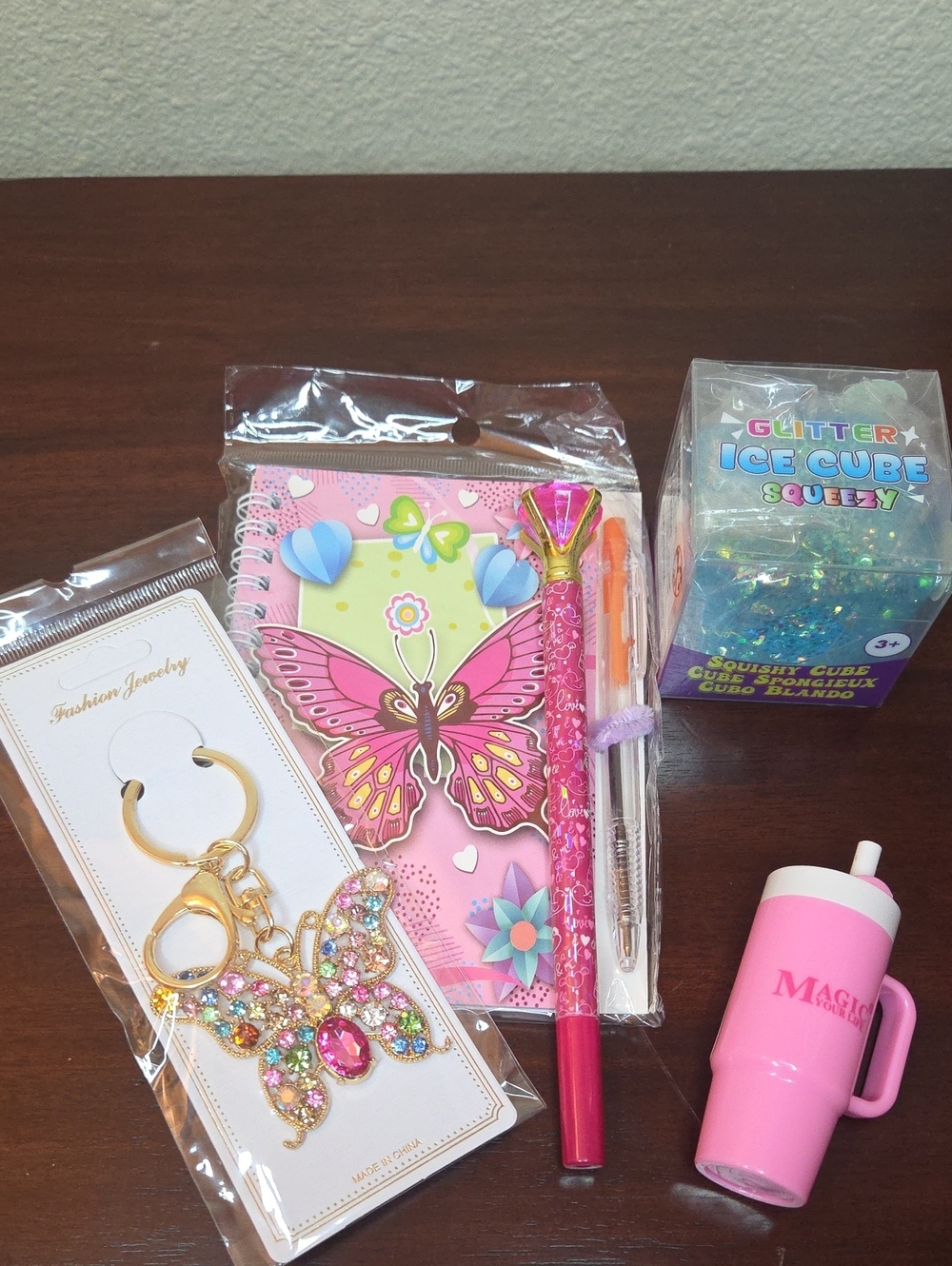 Pink Butterfly Bag Charm, Notebook, Glitter Squeezy Cube, Pen and Lip Balm.
